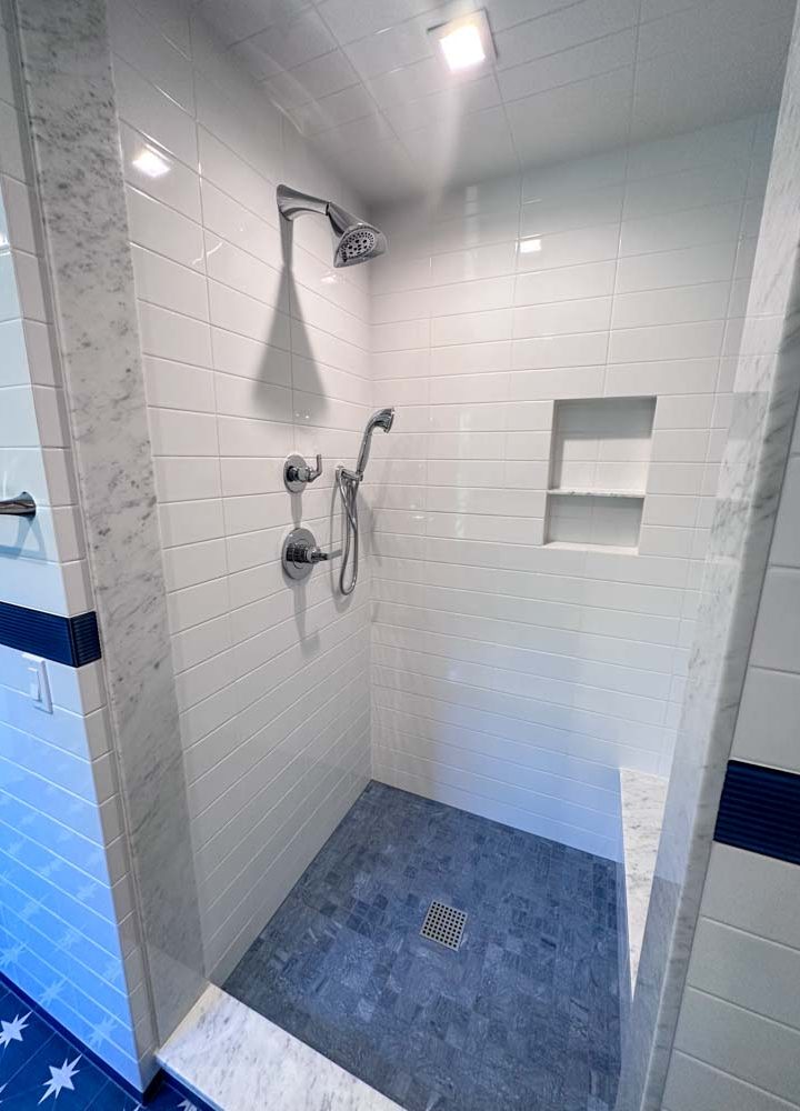 Simple porcelain tiled shower room wall with bath fixtures and niche