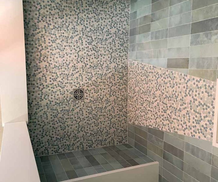Top view perspective of the shower area remodeled with porcelain tiles for the wall and pebbles for the flooring and wall accent