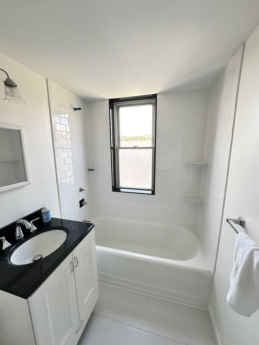 White bathroom with a refinished tub and subway tile surround