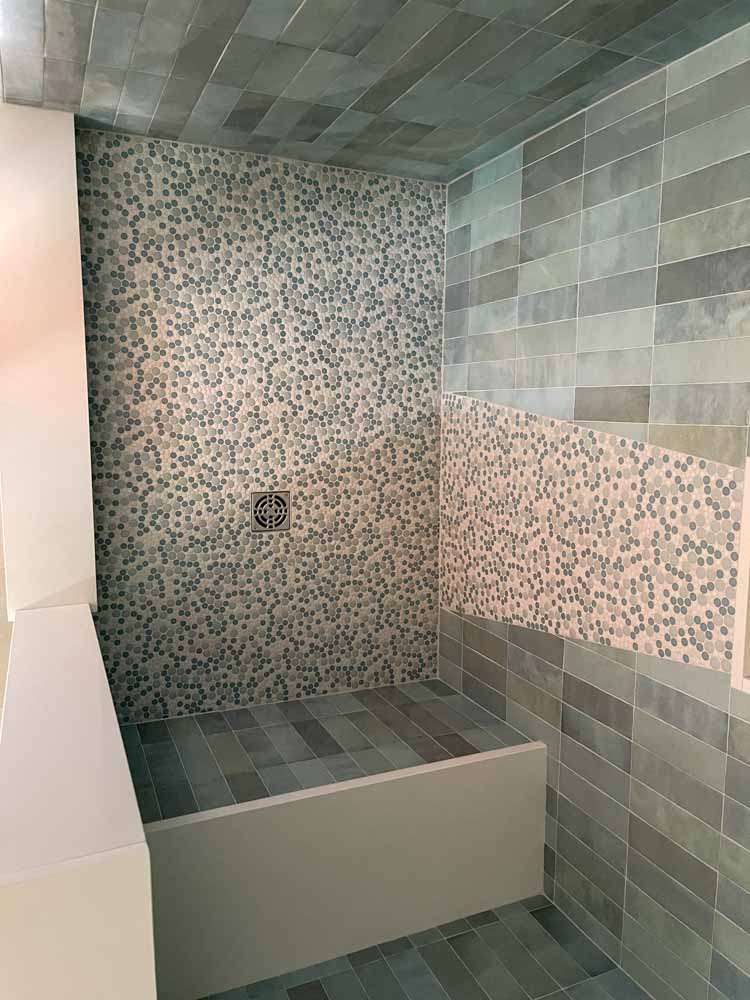 Top view perspective of the shower area remodeled with porcelain tiles for the wall and pebbles for the flooring and wall accent