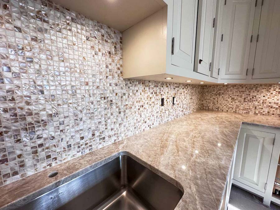 Glass Mosaic Tile for kitchen backsplash complementing the granite countertop that is illuminated by recessed under cabinet lights