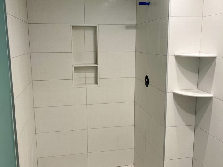 Plain colored ceramic tile wall with shower niche and floating corner shower shelf using the same tile type