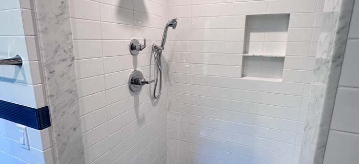 Simple porcelain tiled shower room wall with bath fixtures and niche