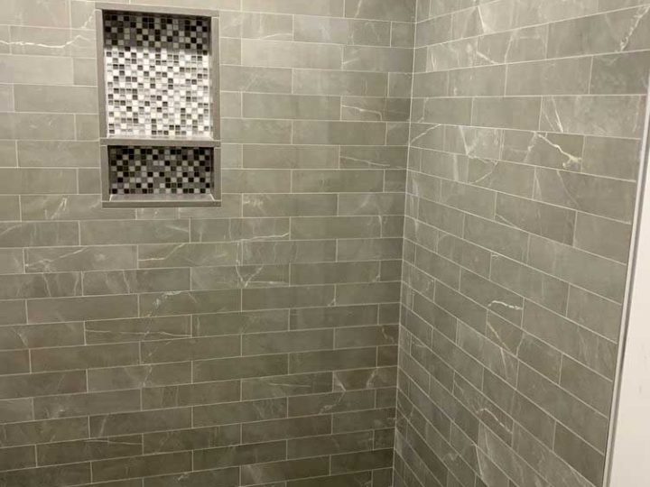 gray natural stone bathroom wall tile in 1/2 offset pattern with mosaic tiled soap dish and shower floor