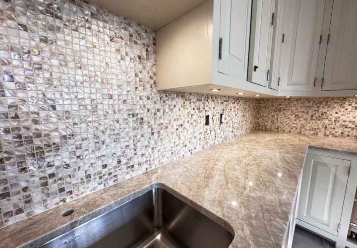 Stone and glass mosaic tiles kitchen backsplash, granite countertop, hanging cabinet with recessed under cabinet lighting